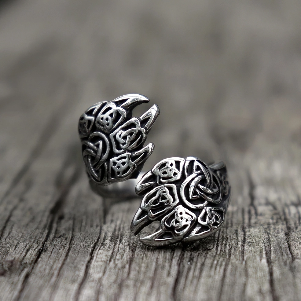 Nordic style bear claw ring side angle on wooden surface - antique silver finish with open wrap design and Celtic knot engravings