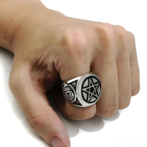 Pentagram metal ring worn on male hand index finger close-up overhead view gothic jewelry
