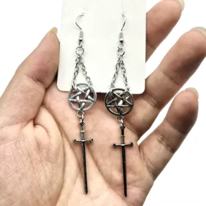 Silver and black pentagram sword dangle earrings displayed in palm - gothic asymmetrical design