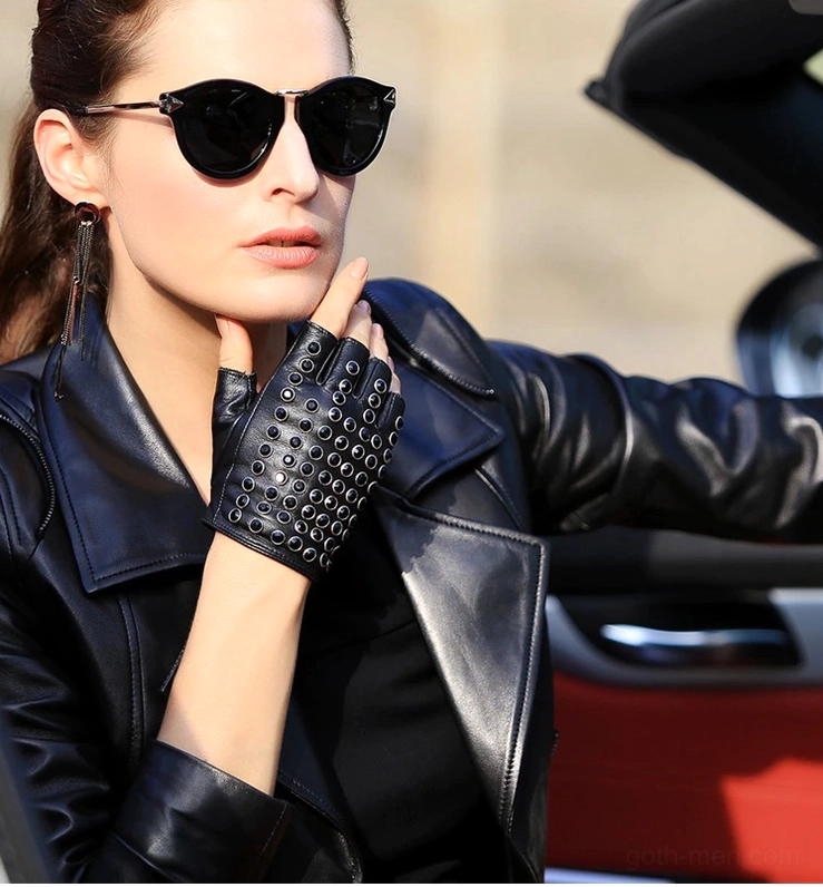 Punk-style half-finger black leather gloves worn by female model with sunglasses in convertible car, biker jacket aesthetic