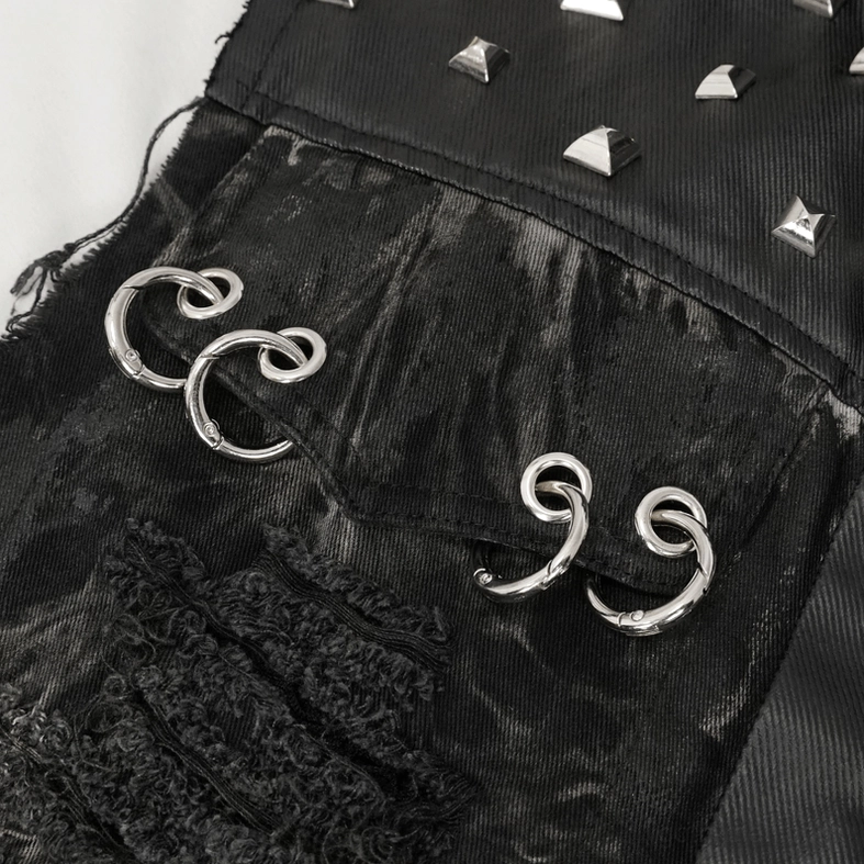 Close-up detail of spiral metal rings and torn frayed fabric on distressed gothic vest