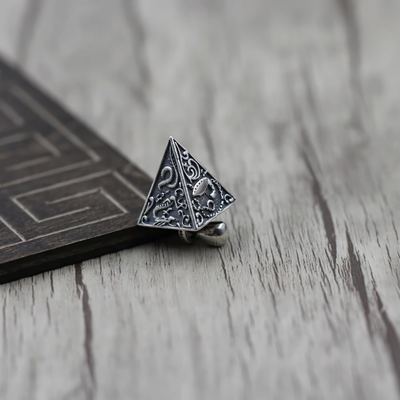 Vintage-style pyramid silver pendant with intricate carved animal and decorative patterns, oblique side perspective