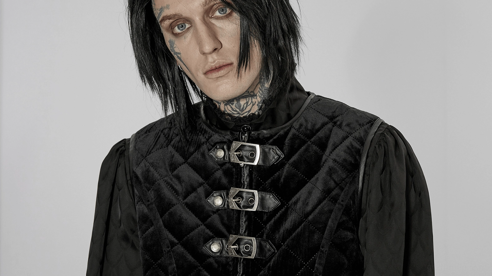 Close-up front view of tattooed model wearing quilted gothic waistcoat with metal buckles