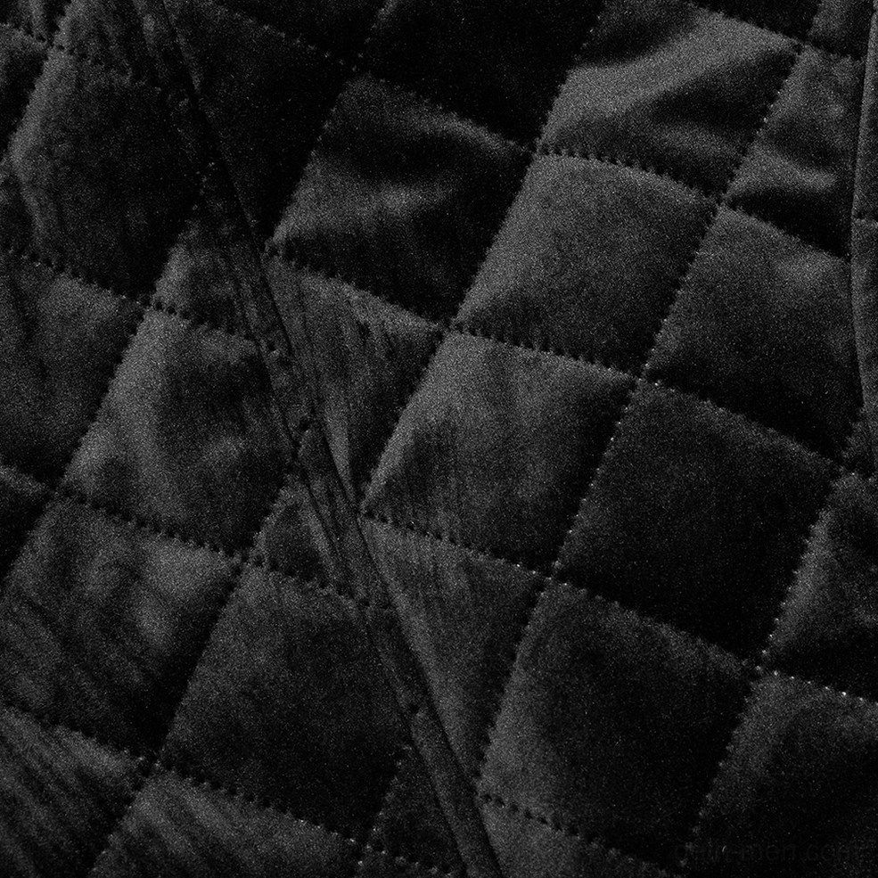 Close-up texture detail of black velvet quilting pattern on gothic waistcoat