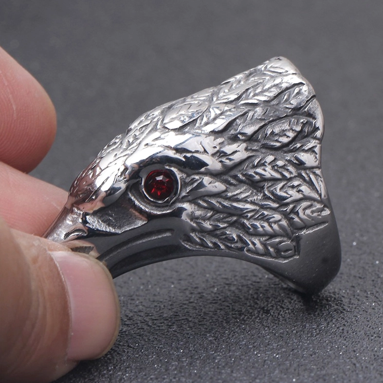 Raven head ring held in hand showing detailed feather patterns and red gemstone eye