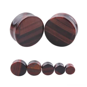 Red tigerite stone ear gauges and tunnel plugs with natural wood grain striping, displayed in multiple sizes from 6mm to 25mm on plain white background, gothic body jewelry collection