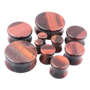Assorted red tigerite stone flesh tunnels and ear expanders showing varied diameters and the distinctive wine-red color with dark burgundy stripes characteristic of tigerite material