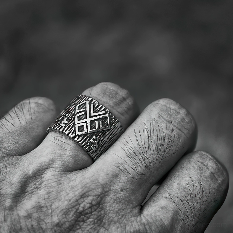 Gothic rune ring worn on male index finger, close-up showing embossed rune patterns and silver finish against dark gray background
