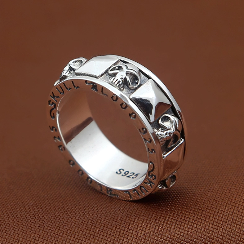 Three-quarter view S925 rotating skull ring with pyramid details and oxidized silver patina