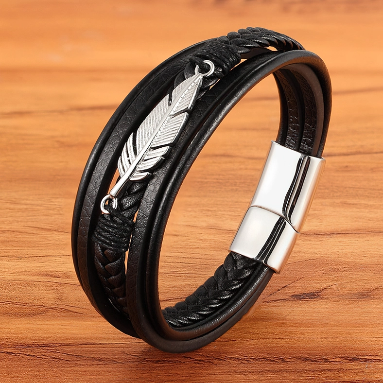 Silver-tone gothic feather leather bracelet on wooden table, showing magnetic clasp and layered leather construction