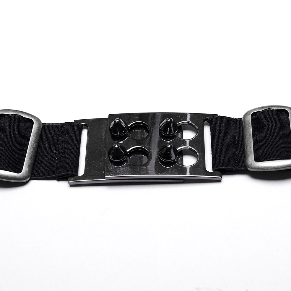 Close-up flat lay of harness buckle featuring spiked gunmetal hardware and black nylon webbing straps