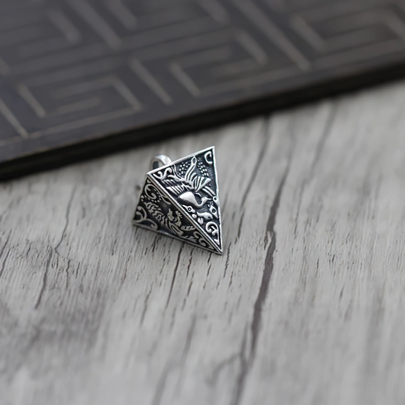 Overhead angled view of oxidized S925 silver pyramid pendant highlighting detailed embossed animal motifs and vintage patina