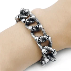 Skull chain bracelet worn on human wrist side close-up detail shot showing worn vintage silver metal finish and heavy gauge construction