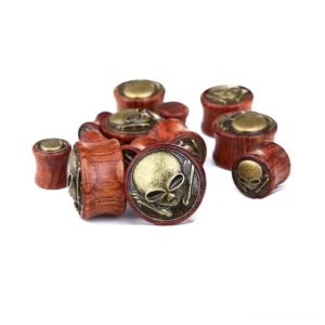 Close-up detail of vintage bronze skeleton skull motif on natural bamboo wood ear tunnels, gothic body jewelry