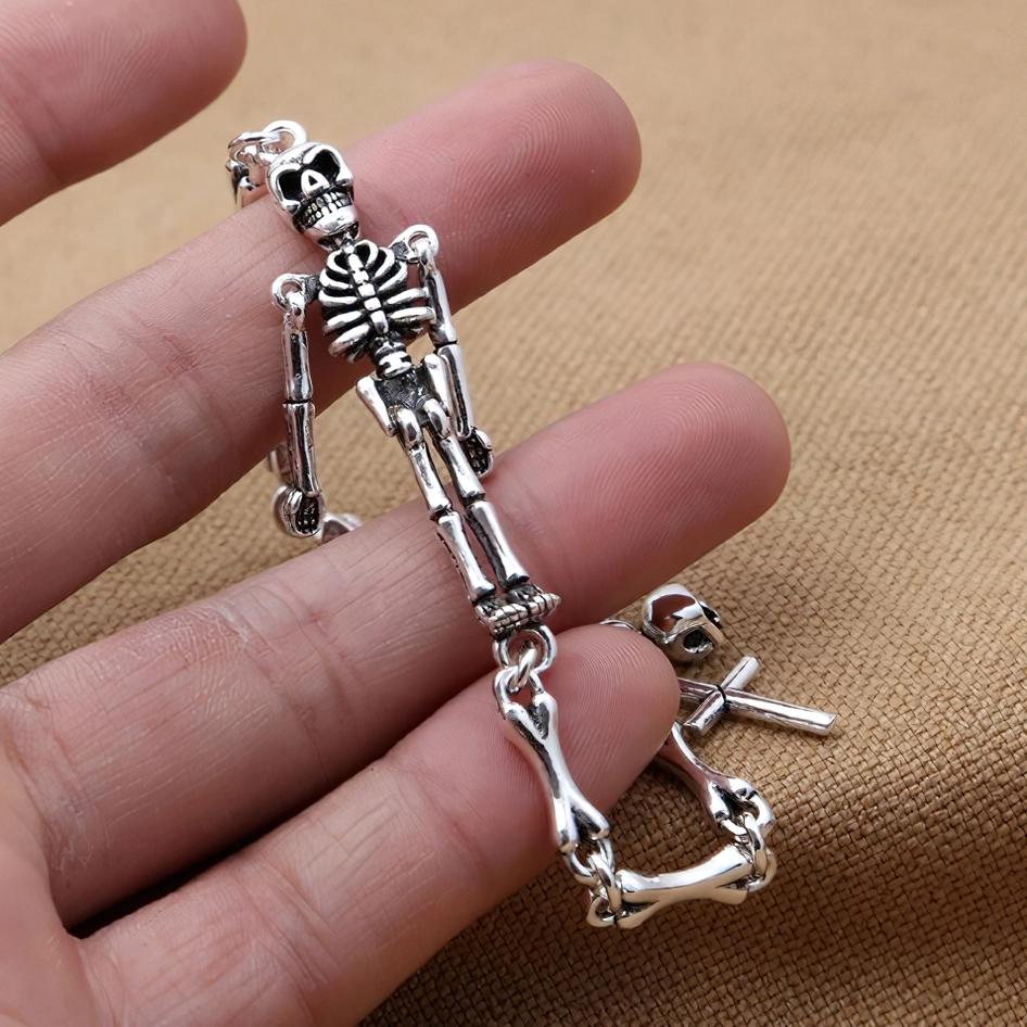 Close-up of sterling silver skeleton bracelet worn on wrist, detailed view of skull pendant toggle clasp and gothic bone chain texture