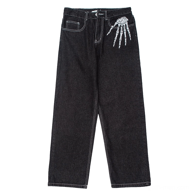 Skeleton hand embroidery gothic jeans front pocket detail, black denim close-up studio view