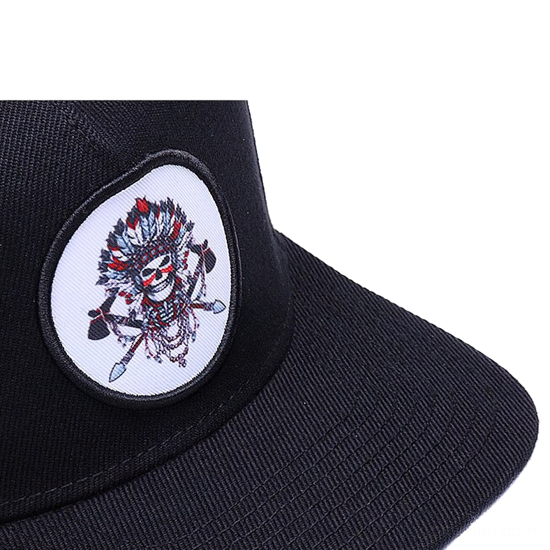 Close-up detail of teardrop-shaped native skull embroidered patch on black flat brim gothic snapback cap
