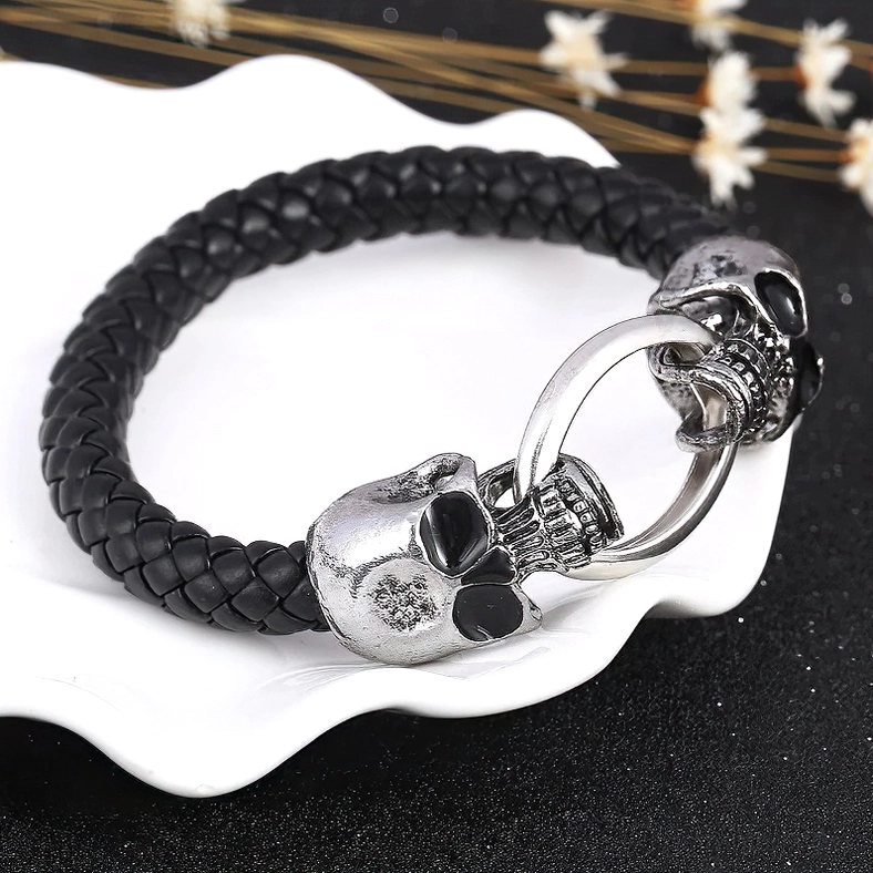 Skull head punk leather bracelet on white ceramic tray - three-quarter angle flat lay product display with silver hardware