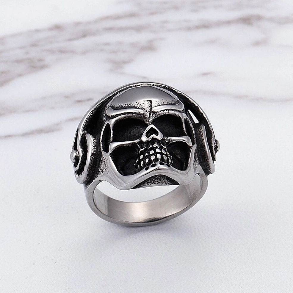 Symmetrical skull headphone ring overhead view, open metal band with detailed carved skull and dual headphone accents
