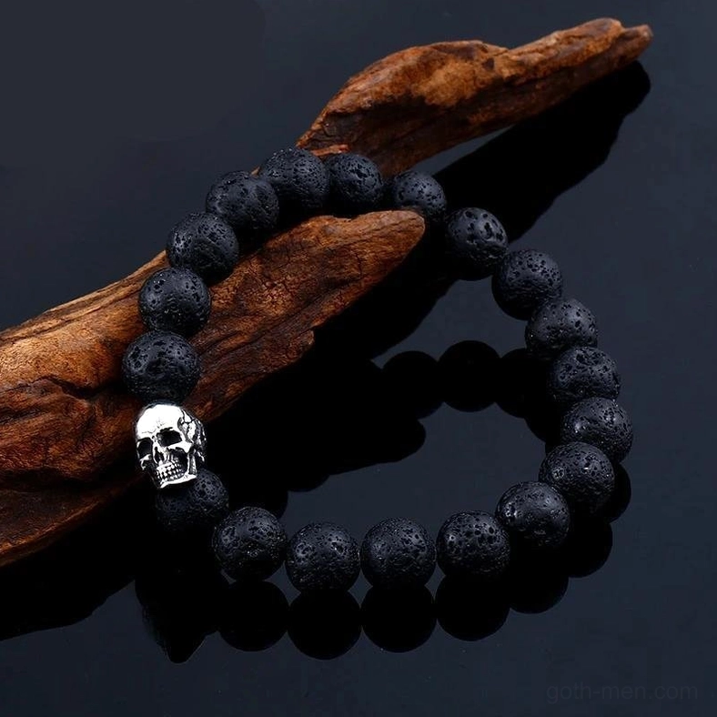Black lava stone skull bracelet detail shot on dark wood and glossy surface showing texture