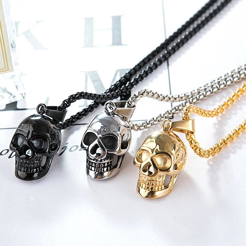 Unisex gothic skull necklace trio displayed flat - black, gold, and silver options overhead shot