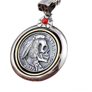 Detailed close-up of gothic skull pendant showing brass inner border, engraved feather and skull pattern, and red gem bail against white background
