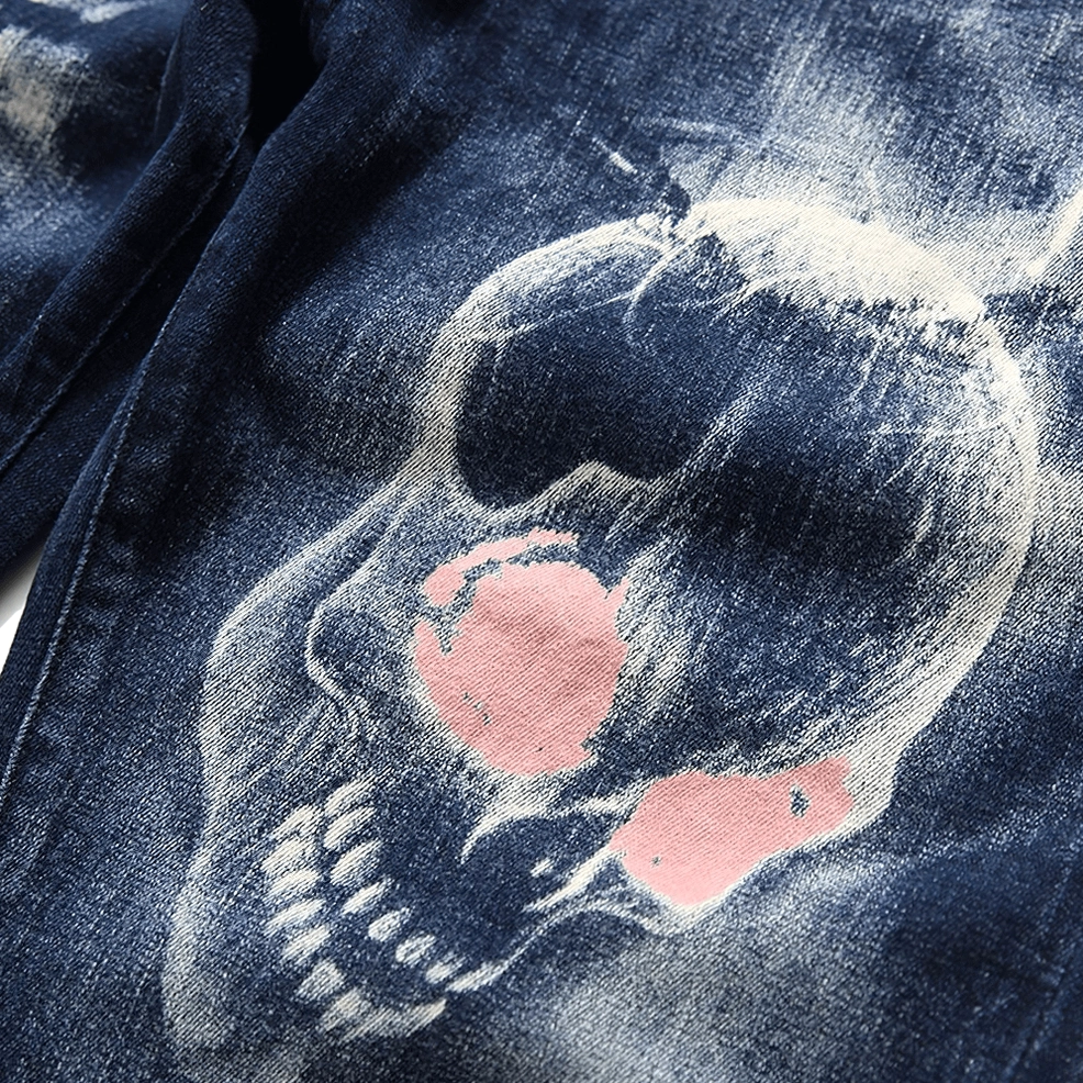 Close-up macro shot of gothic skull print with pink-red accents on faded denim fabric texture