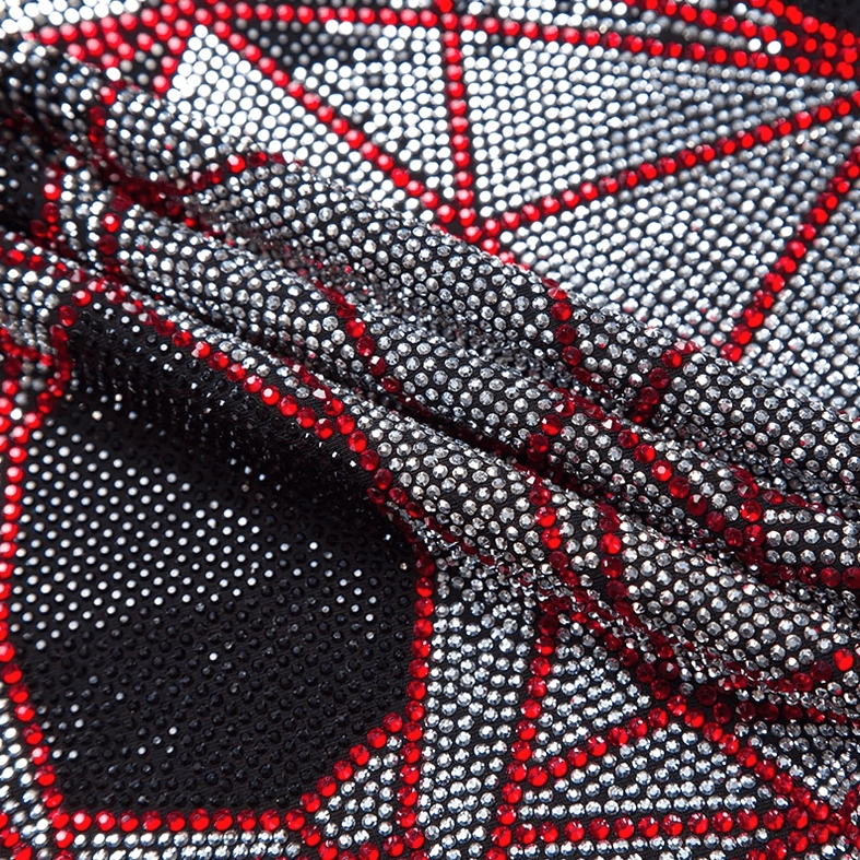 Geometric skull rhinestone appliqué close-up, red and silver crystal details sparkle against dark background