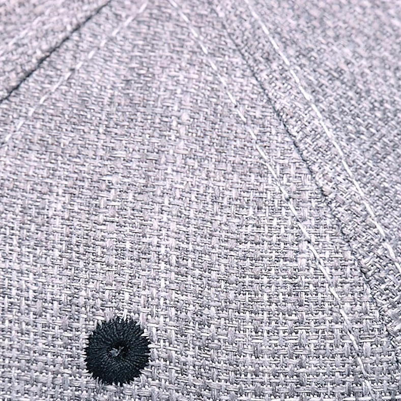 Macro detail of heather gray woven fabric texture and stitching on skull ride hard gothic snapback cap crown, showing material quality and construction