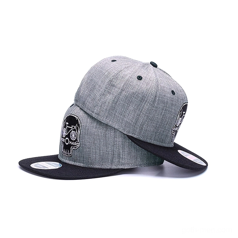 Two stacked skull ride hard gothic snapback caps in oblique rear view, one with hang tag, showing embroidered logo and adjustable buckle mechanism