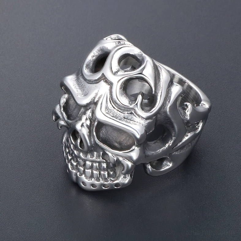 3/4 side profile of stainless steel skull ring on dark gray background, showcasing tribal hollow carvings and realistic skull texture