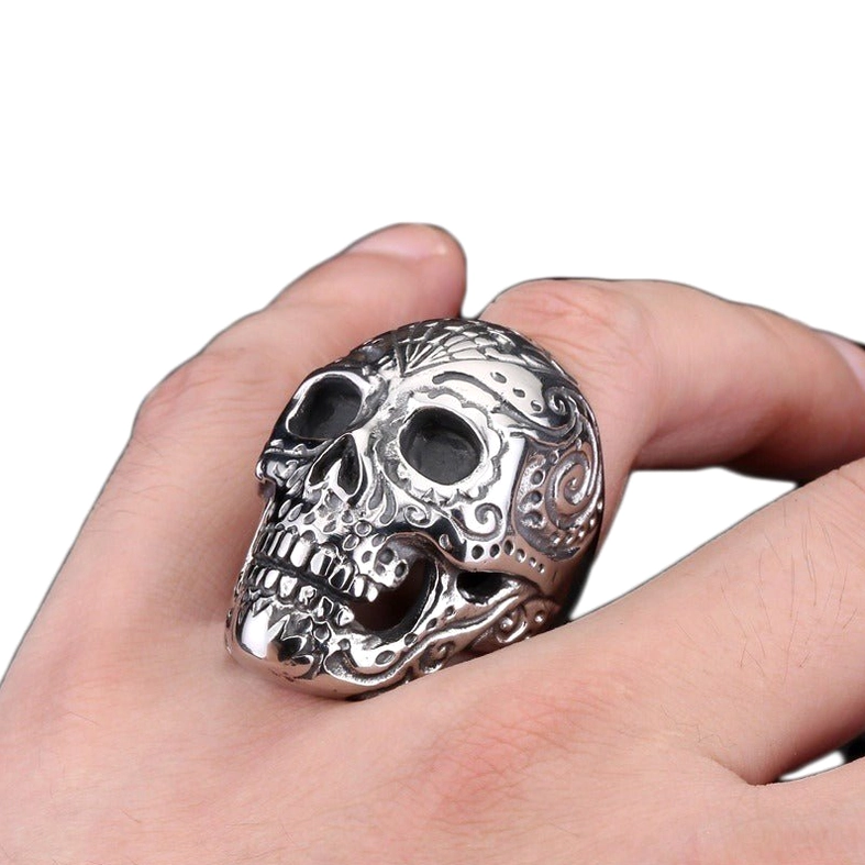 Gothic skull ring worn on male hand, showing intricate carved patterns and polished silver surface, active wear perspective
