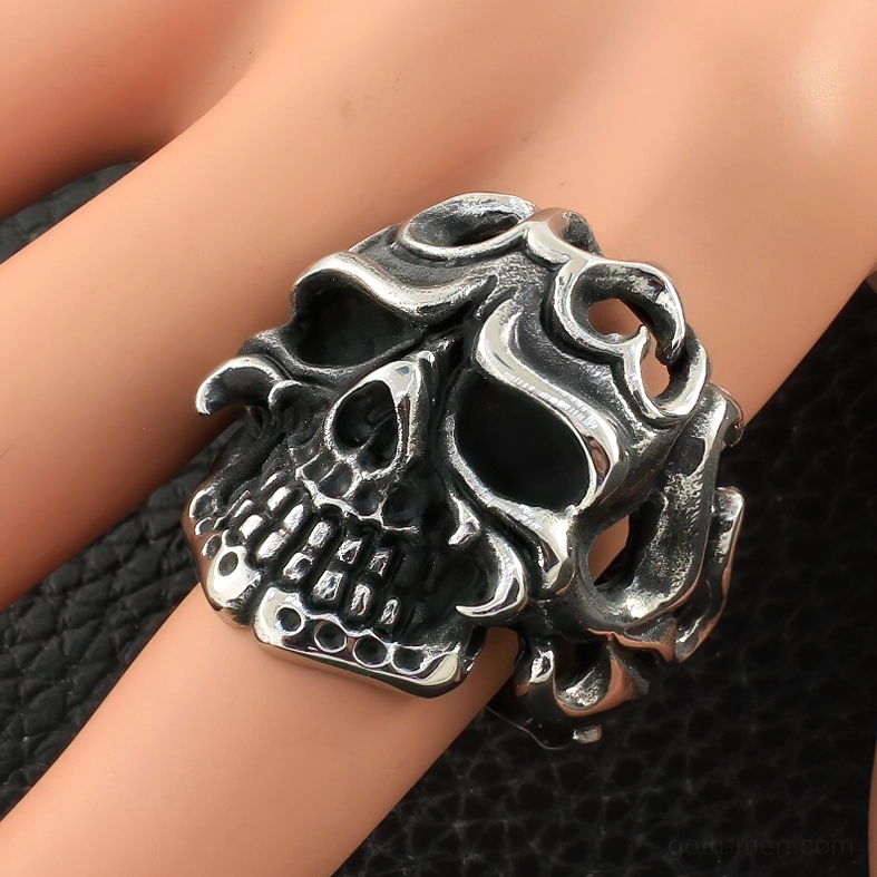 Side view of vintage silver finish gothic skull ring worn on artificial finger model against black leather, demonstrating fit and wearability
