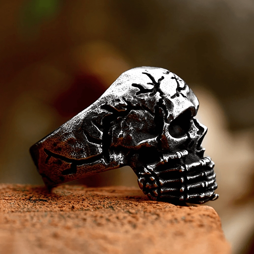 Gothic stainless steel skull ring detail shot showing skeletal fingers and weathered bone-like surface