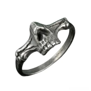 Three-quarter angle of dark metal skull ring displaying bone cross band design and exposed tooth details