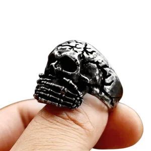 Skull biker ring worn on thumb close-up showing skeleton hand mouth cover and aged metal finish