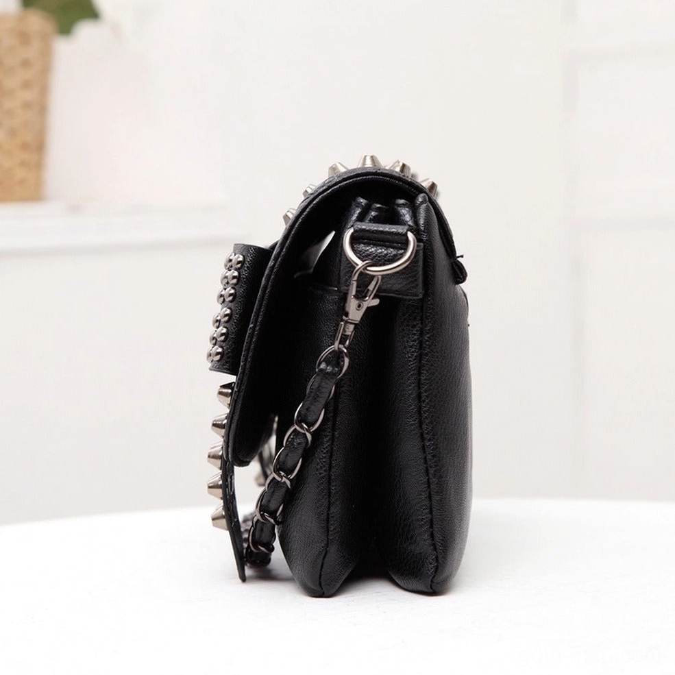 Side profile flat view of black punk gothic studded shoulder bag showing rivet-decorated surface chain hardware and slim leather body