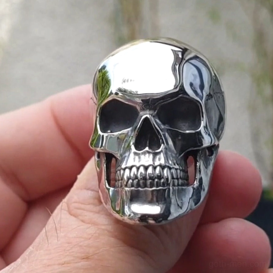 Dark gothic skull ring close-up front view on model fingers displaying precise skull facial features and metal band