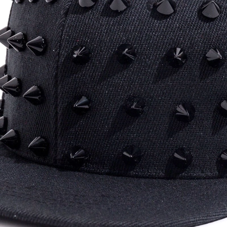 Close-up detail of sharp black cone spikes on textured canvas, gothic punk cap spike texture