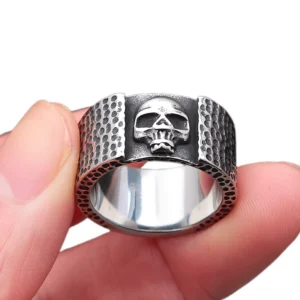Skull biker ring held on human fingers showing vintage silver-black tone and side profile detail