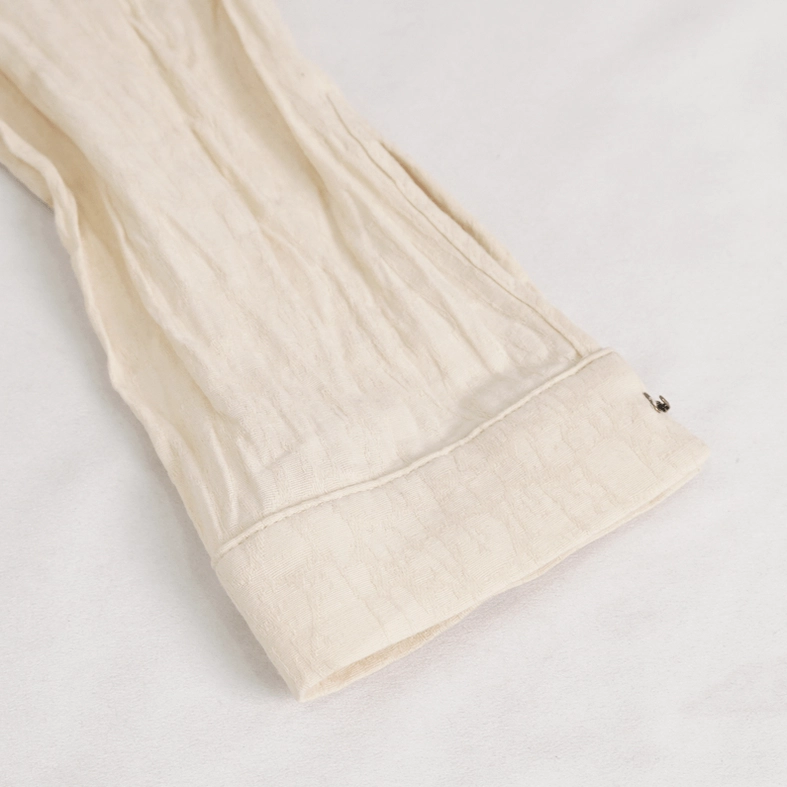 Vintage shirt sleeve cuff detail close-up, displaying cuffed opening with tiny button fastener and wrinkled cotton weave