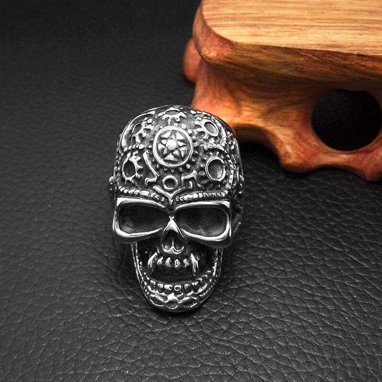 Vintage steampunk skull ring front view on leather cushion wooden stand with carved gear details dark finish
