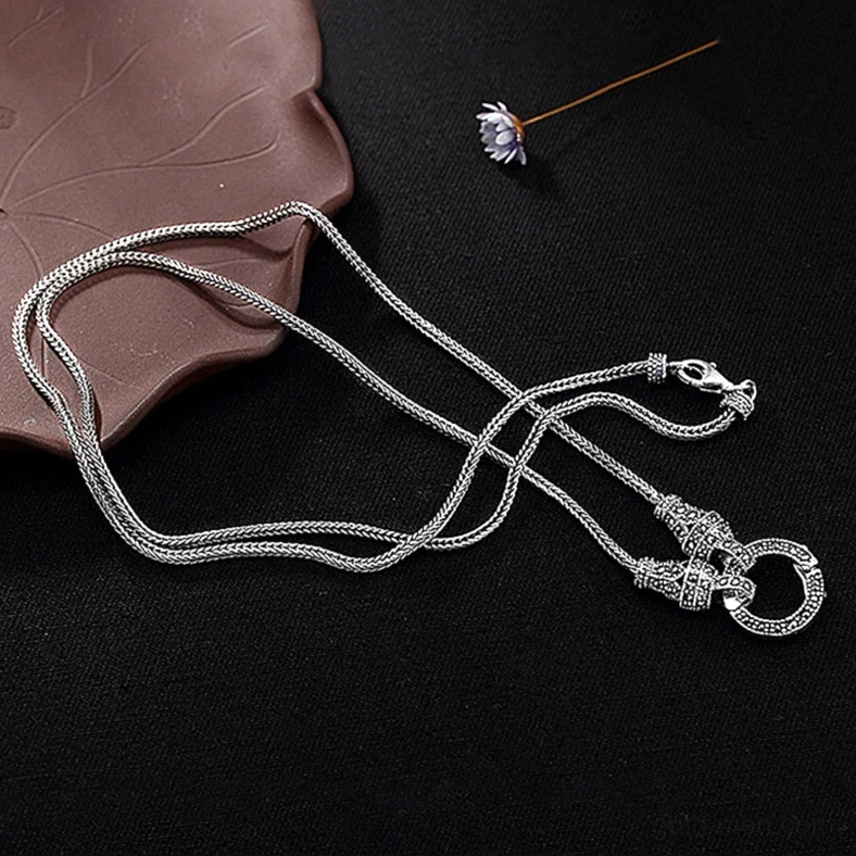 Delicate sterling silver gothic chain necklace overhead flat lay on black background with leaf decor, featuring smooth foxtail chain and marcasite inlaid lobster claw clasp