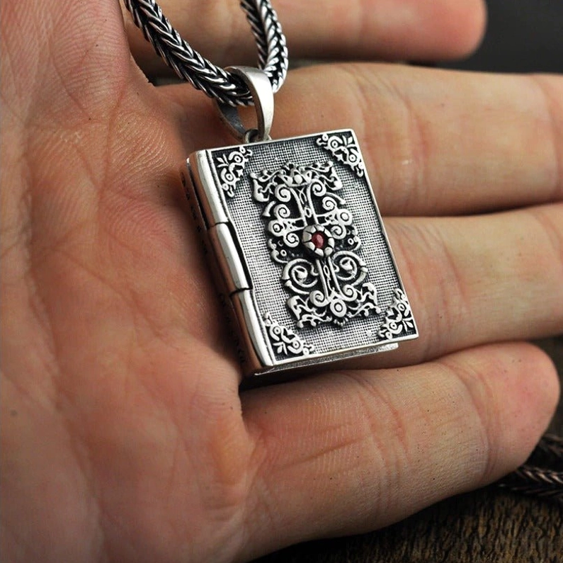 Vintage sterling silver bible locket pendant held in palm showing scale and twisted silver chain detail
