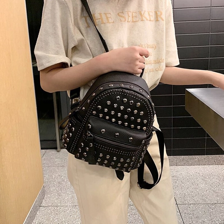 Single shoulder carry demonstration of black rivet gothic backpack worn casually