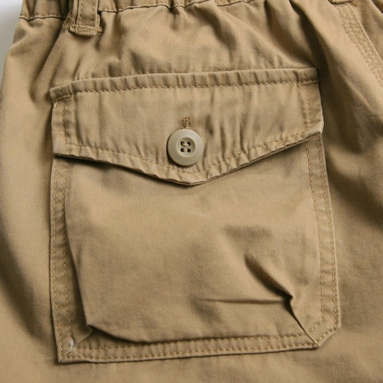Macro close-up of khaki cargo capri shorts buttoned flap pocket with neat reinforced stitching seams