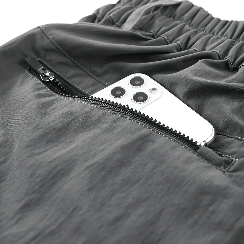 Close-up side view of tactical cargo shorts side zipper pocket with metal zipper hardware and nylon fabric construction