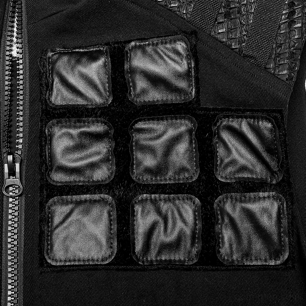 Close-up detail of black denim tactical vest front showing geometric faux leather padded patches and metal zipper