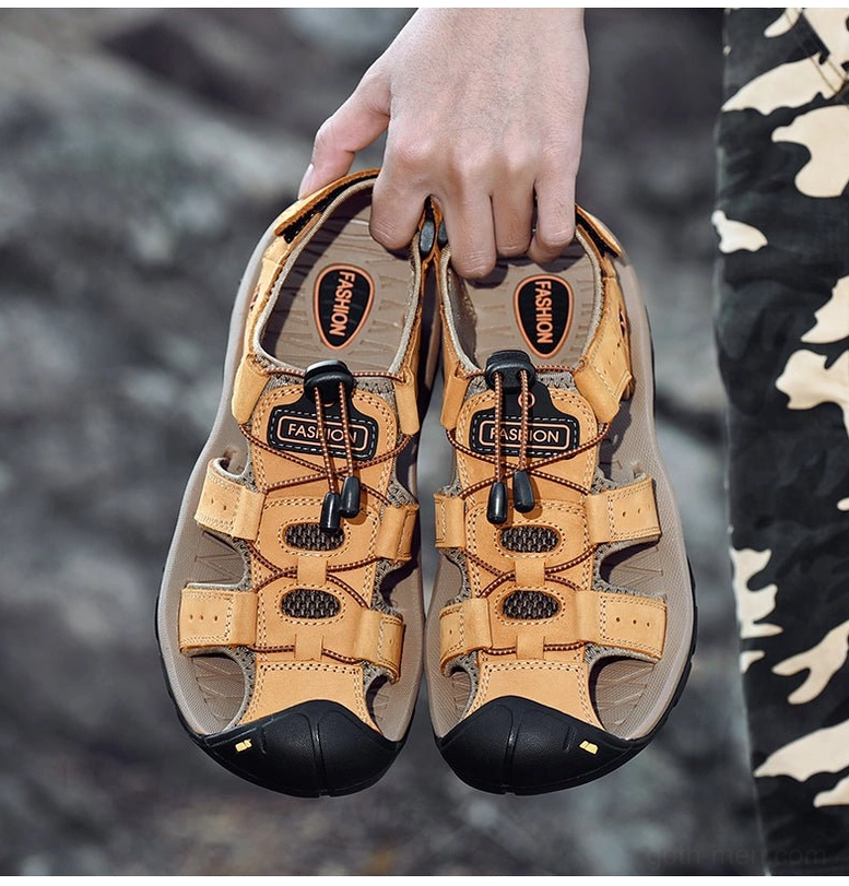 Tan men's genuine leather gothic sandals with closed toe and toggle lace closure - overhead flat view on rocky outdoor background