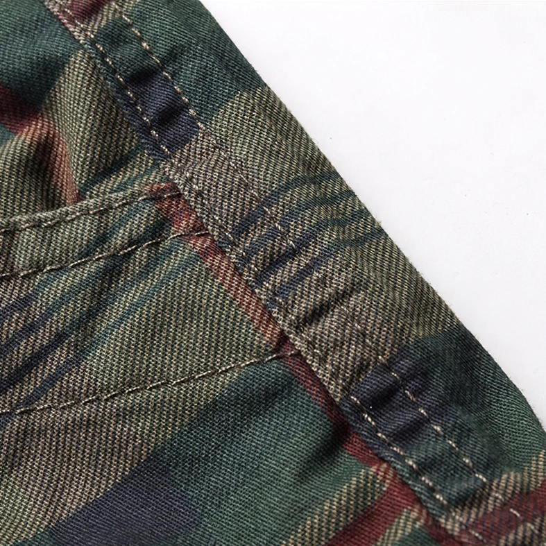 Close-up of tartan plaid fabric pattern with dark green, red and navy stripes and stitched seams